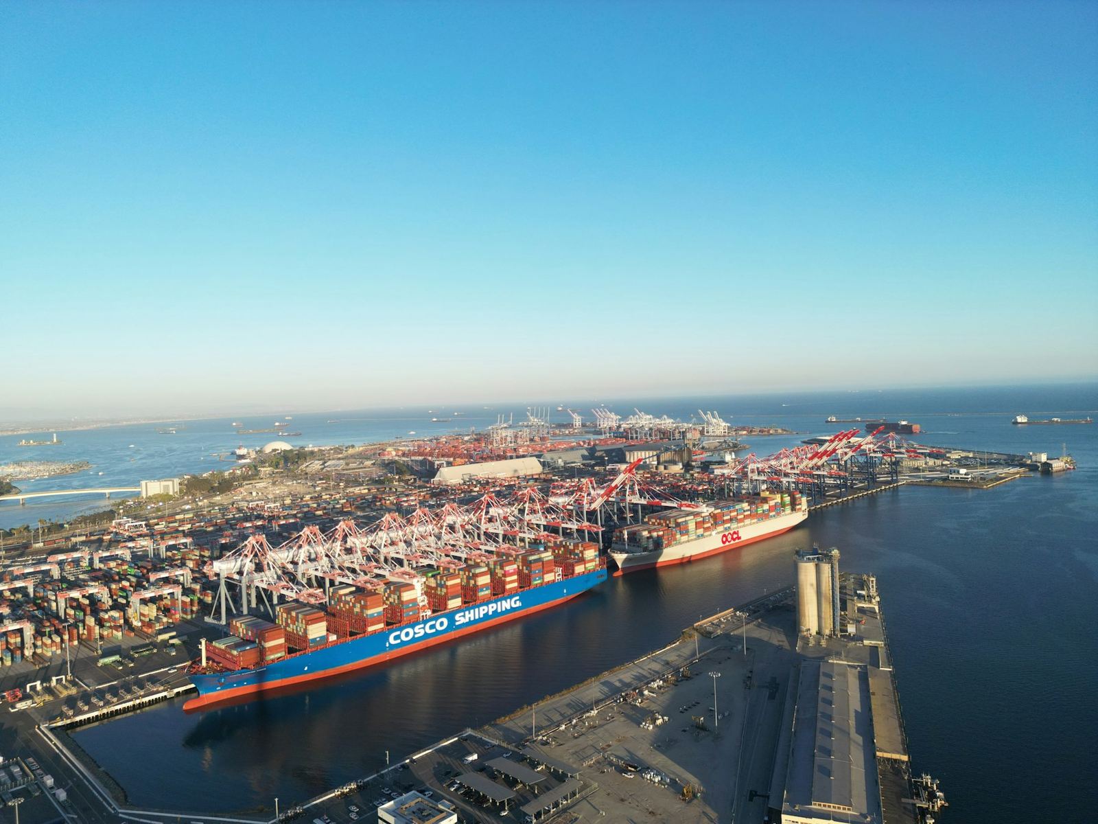 Aerial view of a large container vessel and port terminal on clear blue water